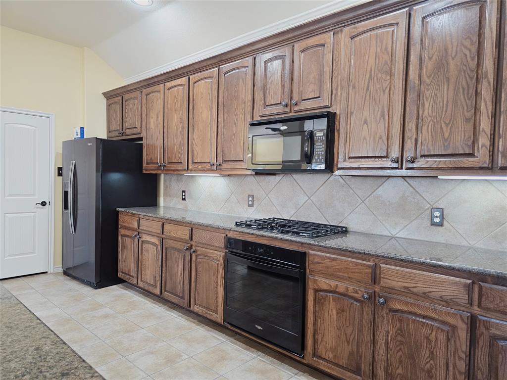 1800 Lancaster Gate Allen, TX 75013 - Photo 7 of 20 a kitchen with granite countertop a stove a sink dishwasher and a refrigerator with wooden cabinets