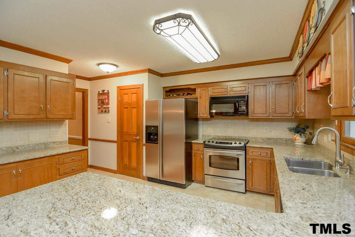 8101 Winstone Court Raleigh, NC 27615 - Photo 5 of 25 Kitchen features stainless steel appliances, tile back-splash and breakfast bar. Notice the picture window that overlooks the private yard.