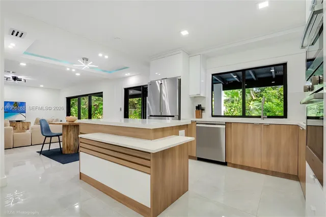 a kitchen with kitchen island a large counter top space a sink stainless steel appliances and windows