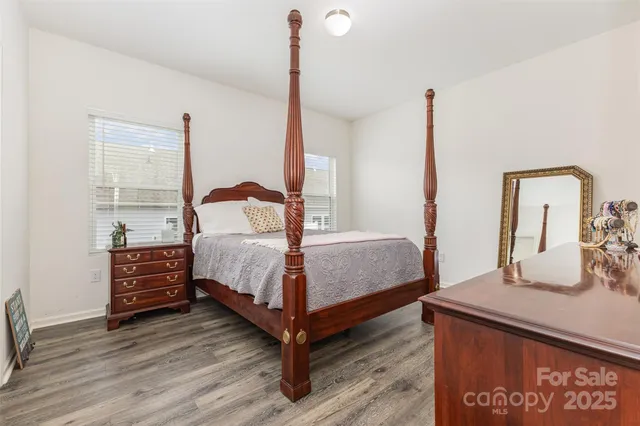 a bedroom with a bed a dresser with wooden floor