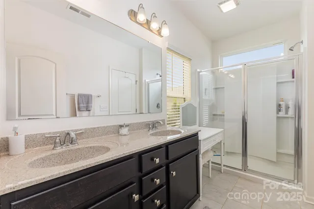 a bathroom with double vanity sinks and a shower