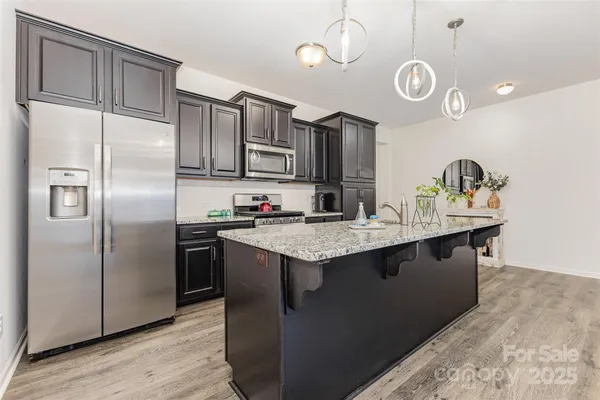 a kitchen with stainless steel appliances granite countertop a sink a stove and a refrigerator