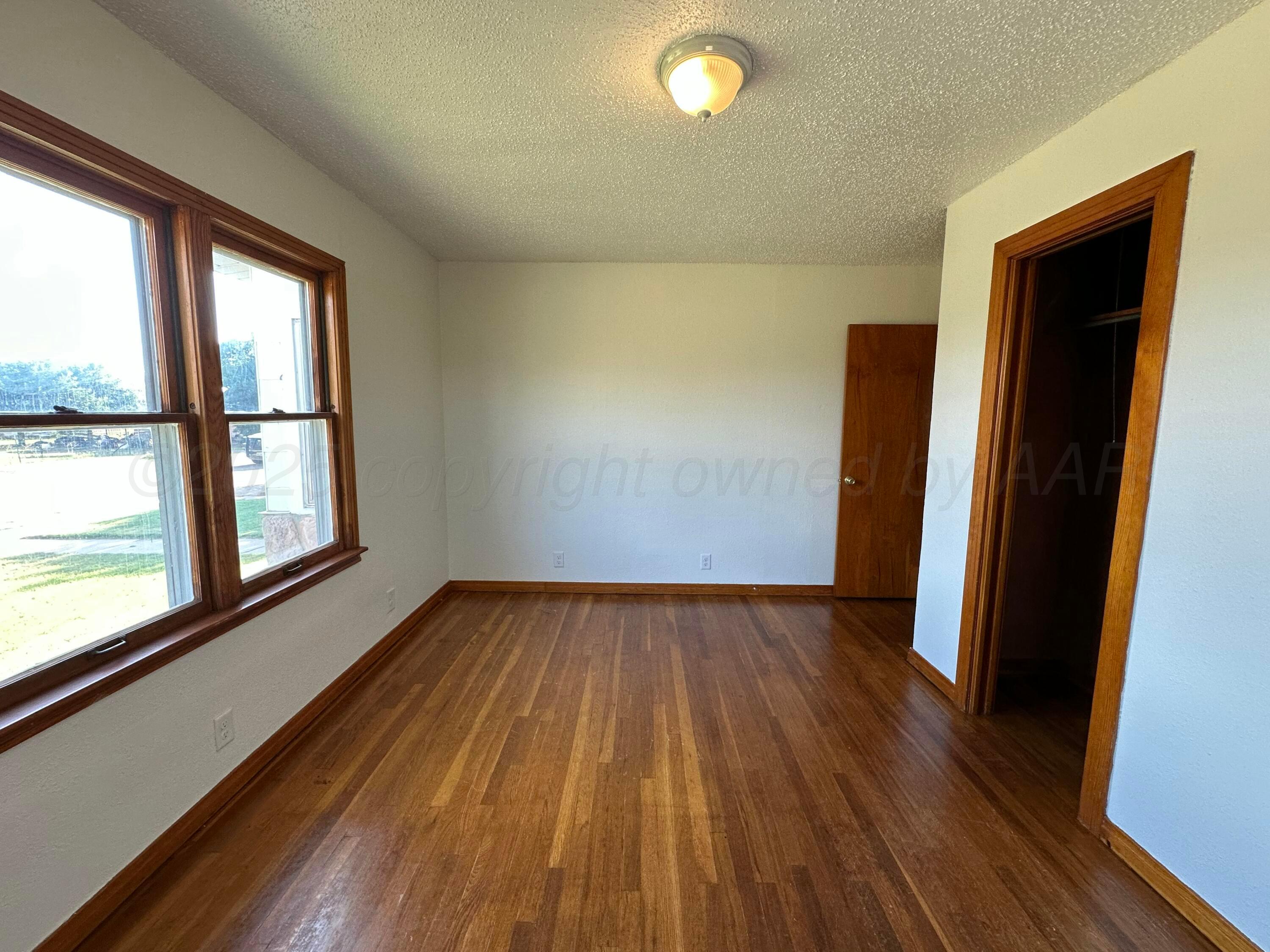 913 Bell Avenue Turkey, TX 79261 - Photo 15 of 18 an empty room with wooden floor and windows