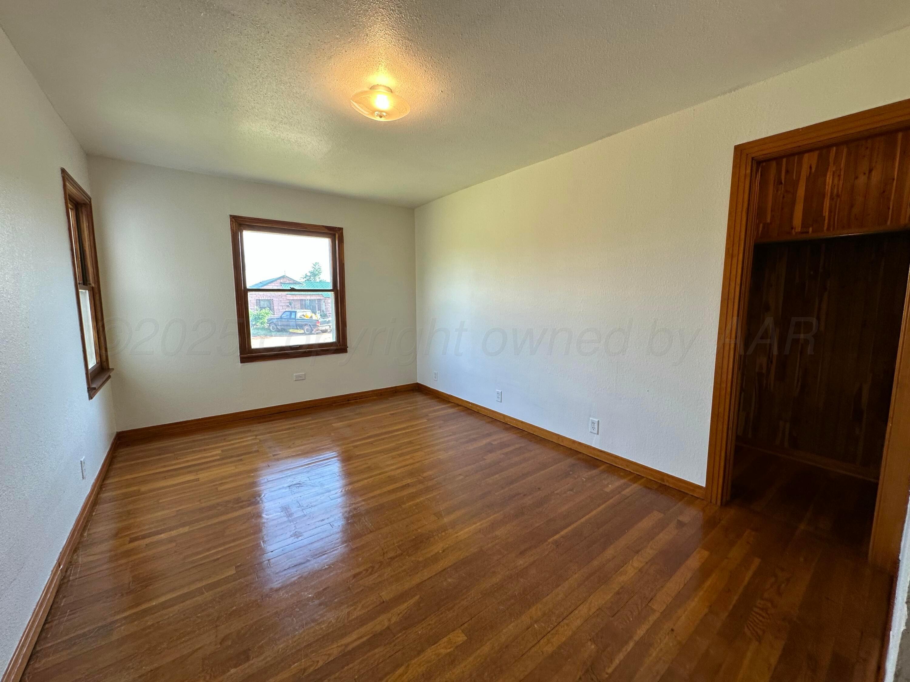913 Bell Avenue Turkey, TX 79261 - Photo 8 of 18 a view of an empty room with wooden floor and a window