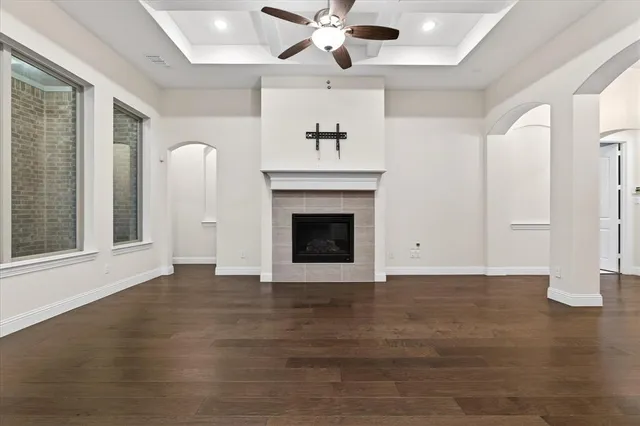 an empty room with wooden floor fireplace and ceiling fan