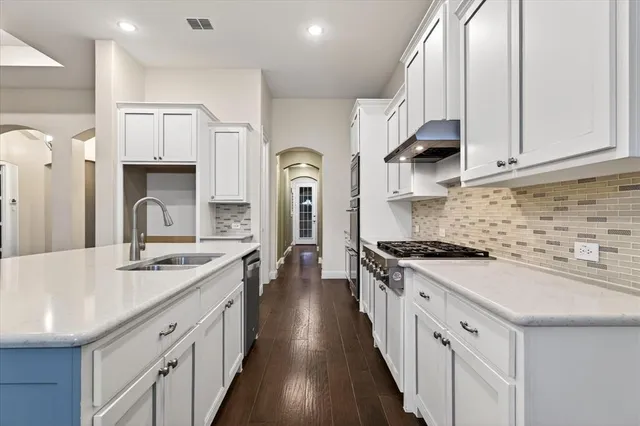 a kitchen with stainless steel appliances granite countertop a sink stove and cabinets