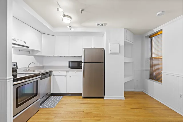 a kitchen with a refrigerator a stove top oven and cabinets