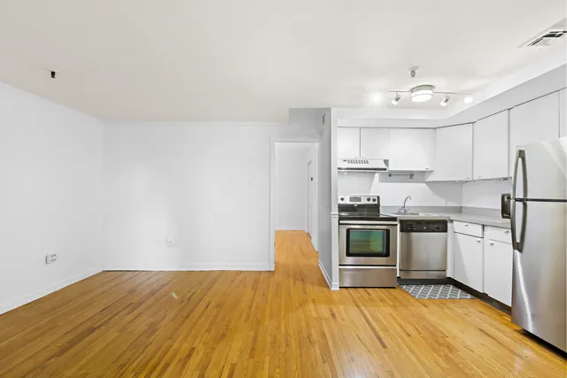 a kitchen with stainless steel appliances a stove a sink cabinets and wooden floor