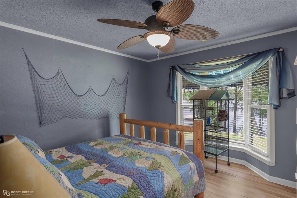 10865 Ferry Lake Road Oil City, LA 71061 - Photo 24 of 36 Bedroom featuring wood finished floors, a textured ceiling, and a ceiling fan