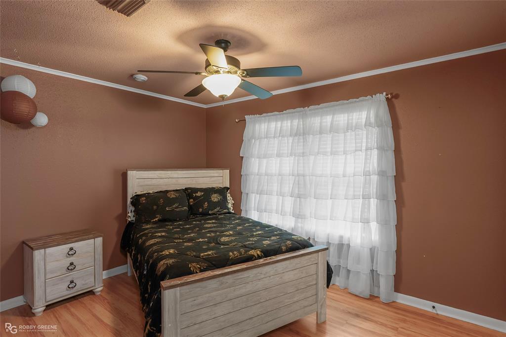 10865 Ferry Lake Road Oil City, LA 71061 - Photo 25 of 36 Bedroom with a textured ceiling, wood finished floors, crown molding, and ceiling fan