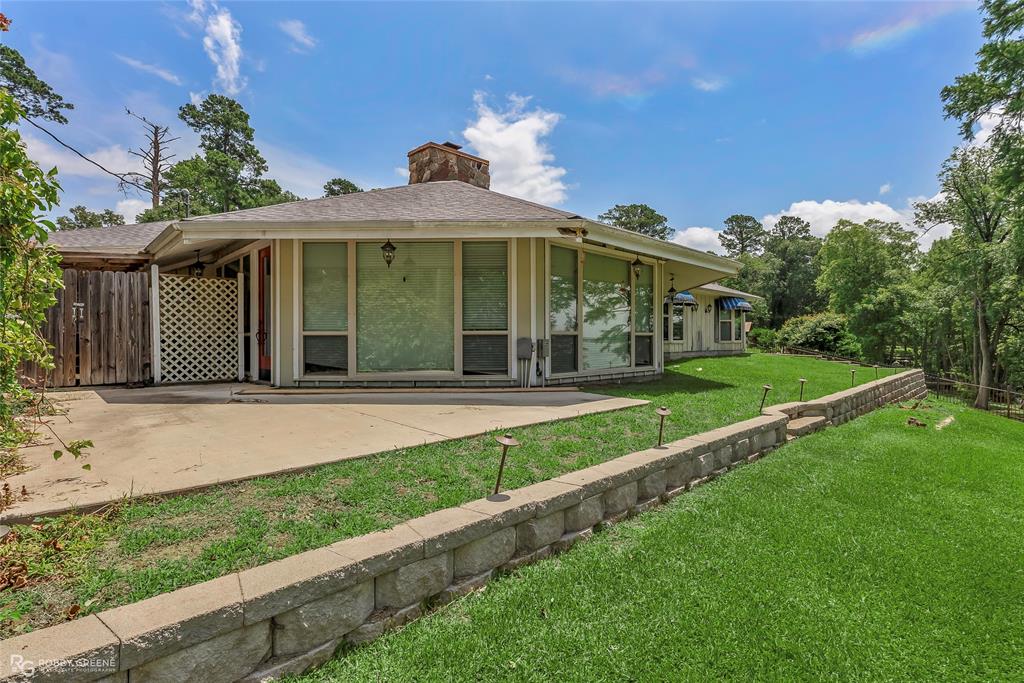 10865 Ferry Lake Road Oil City, LA 71061 - Photo 4 of 36 View of back of facade featuring a patio area, a chimney, and a shingled roof