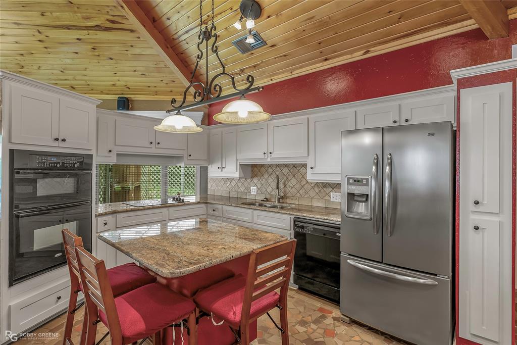 10865 Ferry Lake Road Oil City, LA 71061 - Photo 10 of 36 Kitchen with black appliances, wood ceiling, white cabinetry, tasteful backsplash, and a center island