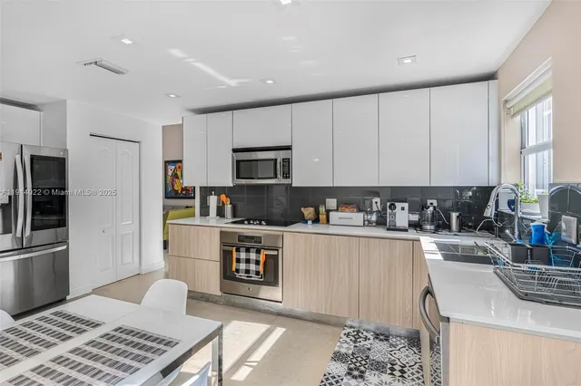 a kitchen with a refrigerator a stove top oven a sink dishwasher and white cabinets with wooden floor