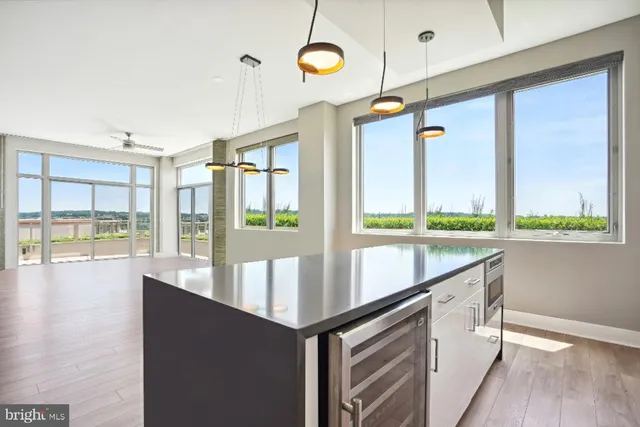 an empty room with wooden floor and windows with curtains