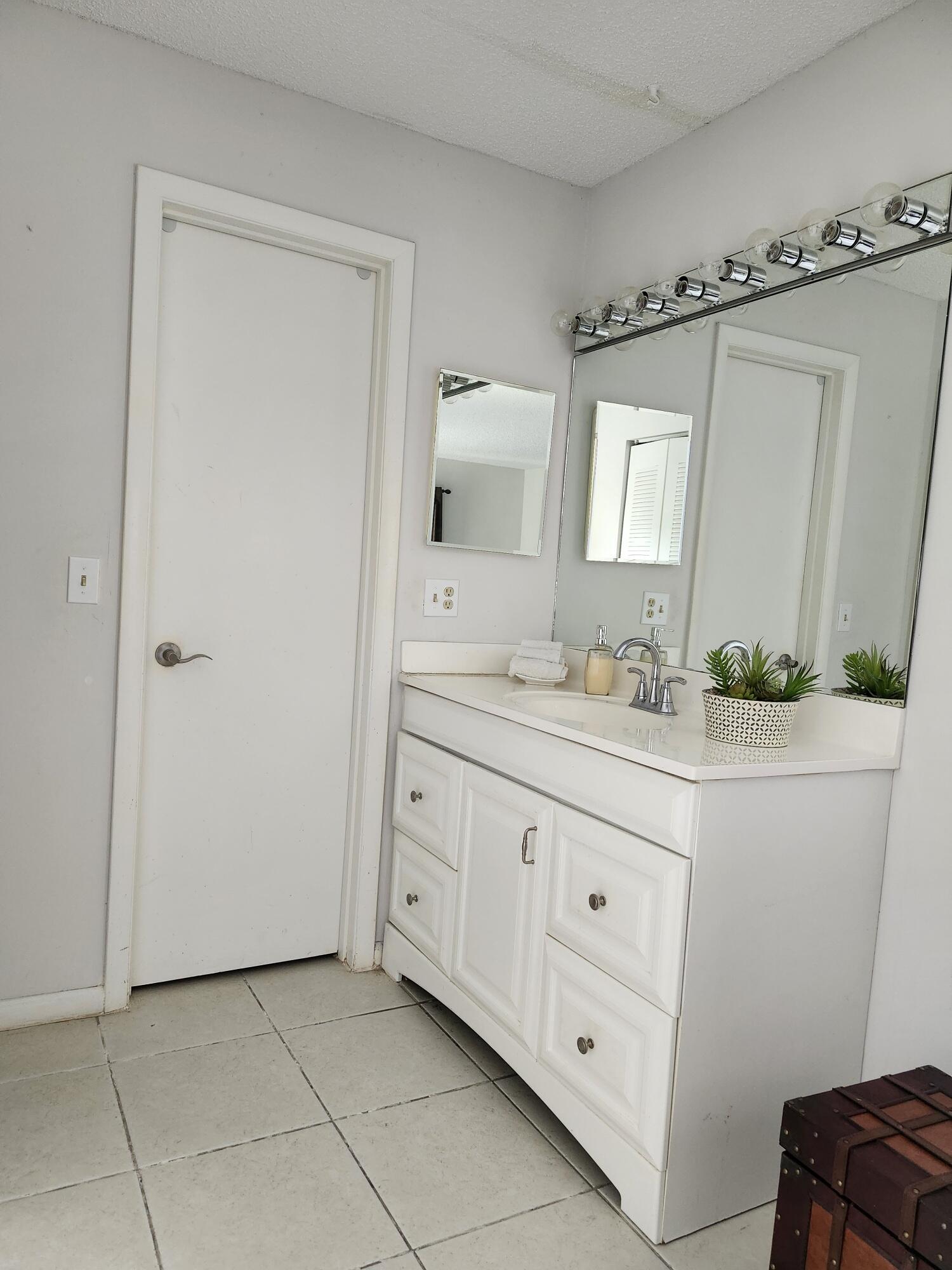 1141 Calamondin Terrace, Unit 101 Delray Beach, FL 33445 - Photo 15 of 21 a bathroom with a granite countertop sink a mirror a vanity and a window