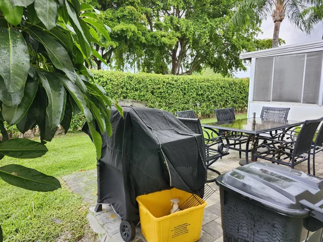 a view of a backyard with table and chairs potted plants and large tree