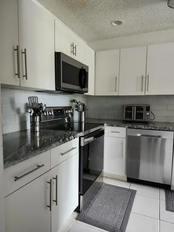 a kitchen with granite countertop white cabinets and white appliances