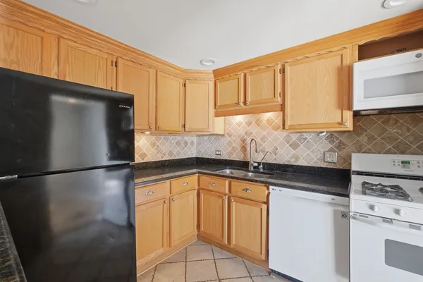 a kitchen with stainless steel appliances granite countertop a refrigerator a stove and a sink