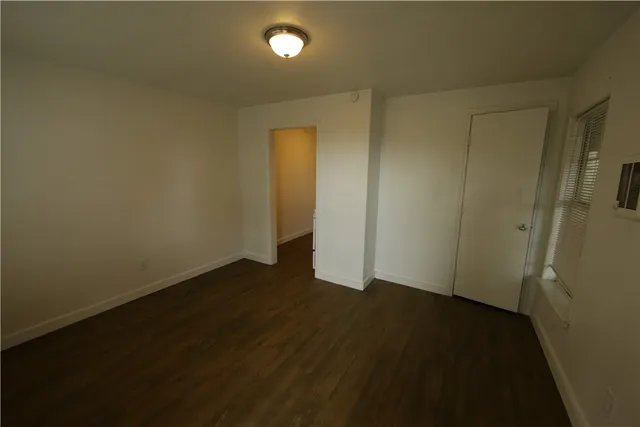 an empty room with wooden floor and windows with curtains