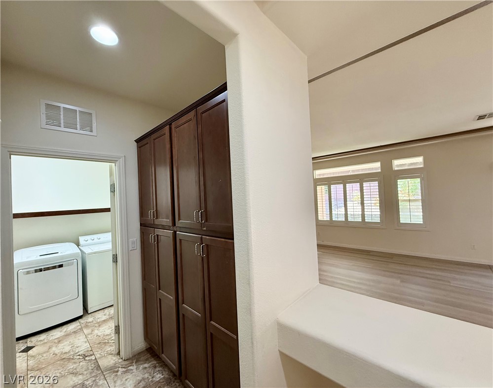 6459 Parrot Ridge Court Las Vegas, NV 89139 - Photo 11 of 23 Functional laundry space with storage cabinets and tile flooring leads to an adjacent living area.
