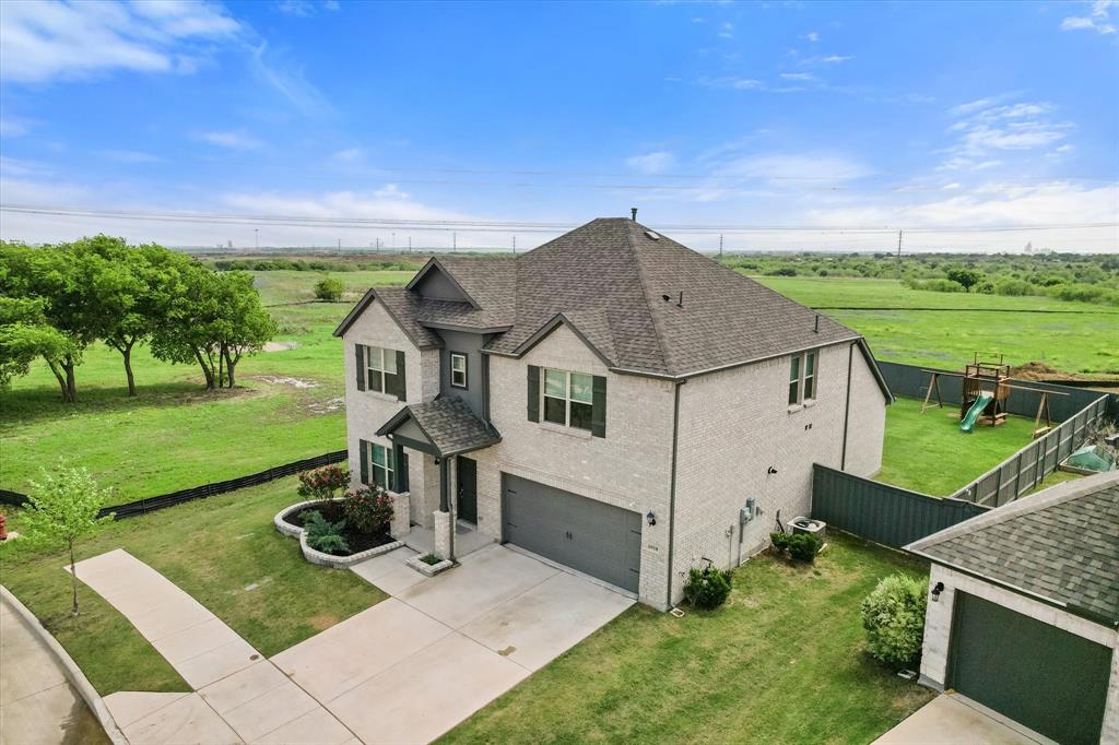 6910 Prairieside Trail Venus, TX 76084 - Photo 2 of 40 The property features a two-story residence with a light-colored brick & stone exterior and dark roof, complemented by a well-maintained lawn and paved driveway.