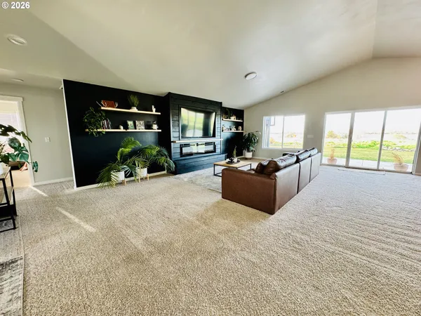 a kitchen with stainless steel appliances granite countertop a refrigerator a sink dishwasher a stove top oven a dining table and chairs with wooden floor