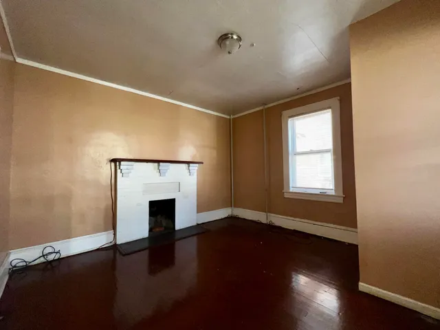 a view of empty room with wooden floor and fireplace