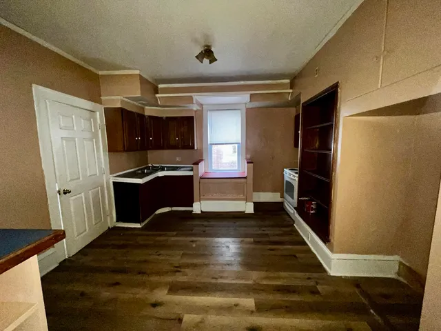a living room with stainless steel appliances wooden floor and a window