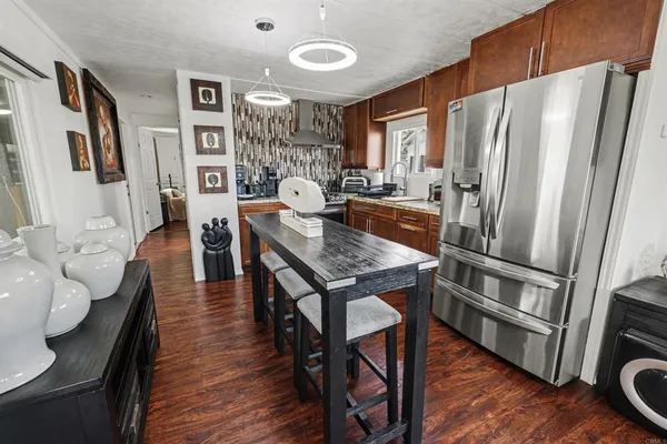a kitchen with stainless steel appliances granite countertop a refrigerator a stove a sink a dining table and chairs with wooden floor