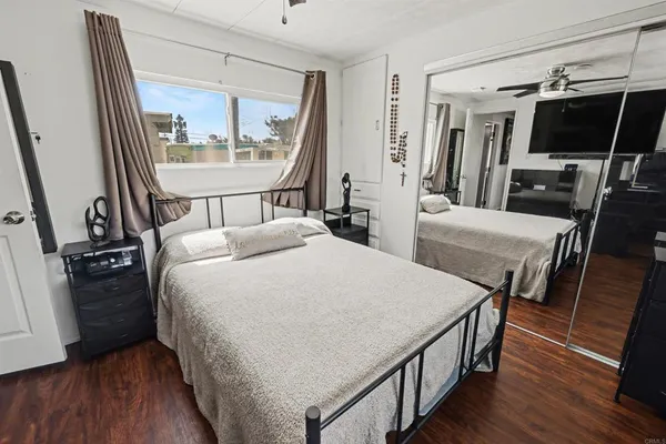 a bedroom with a bed a large window and wooden floor