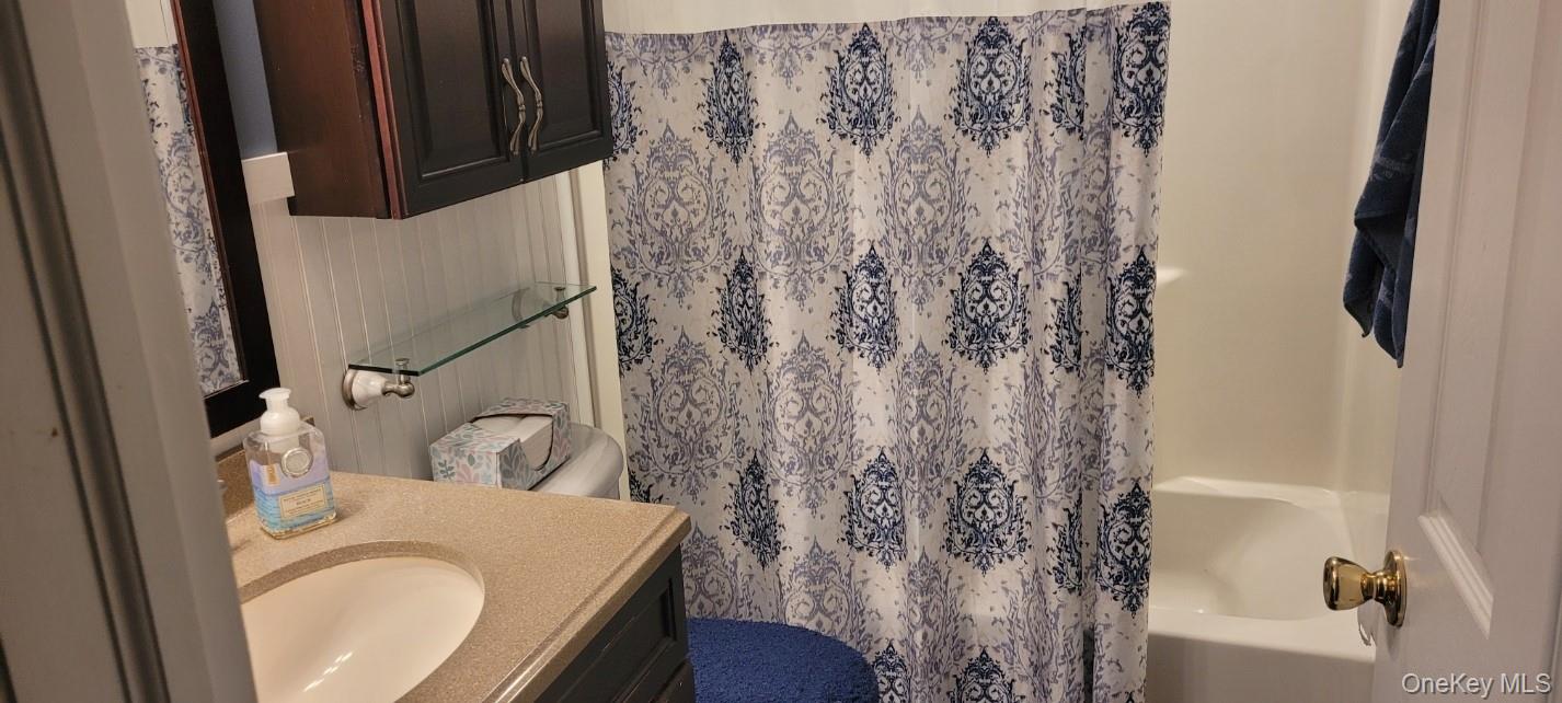 312 Riley Avenue Calverton, NY 11933 - Photo 16 of 30 Bathroom featuring a single vanity with an integrated sink, beige countertop, and dark wood-finish cabinetry
