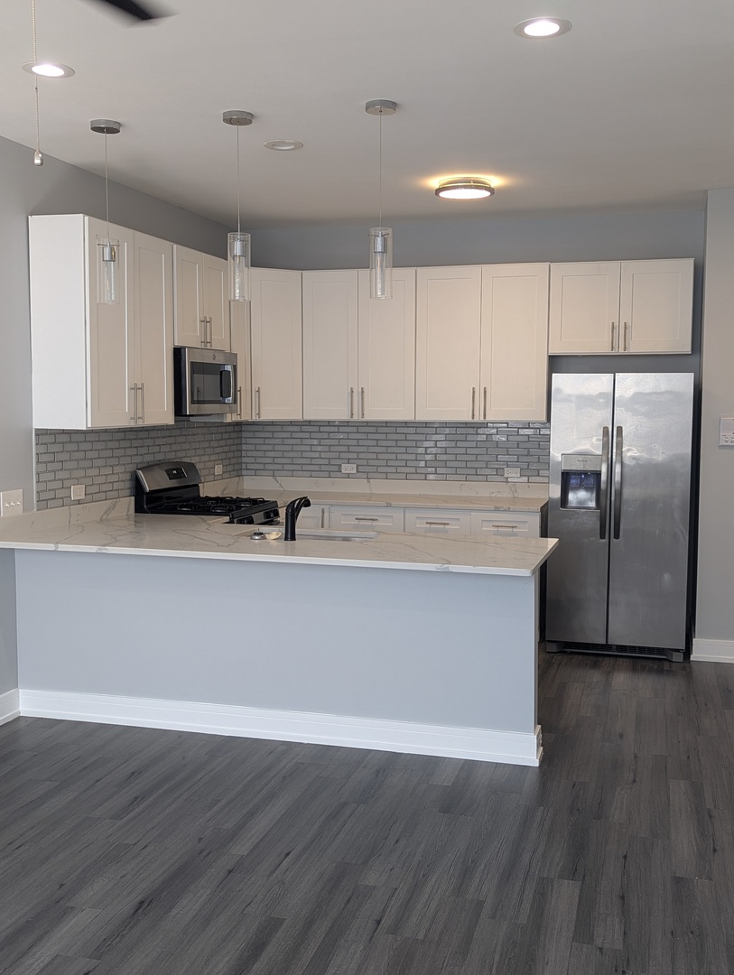 3925 South Indiana Avenue, Unit 3 Chicago, IL 60653 - Photo 5 of 11 a view of kitchen with stainless steel appliances granite countertop a stove a refrigerator a sink and white cabinets with wooden floor