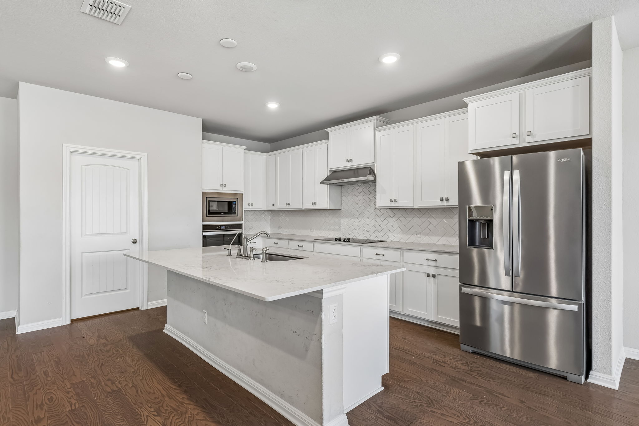 4009 Milano River Road Hutto, TX 78634 - Photo 8 of 40 Gleaming hardwood floors complement a spacious central island and modern cabinetry in this culinary space.