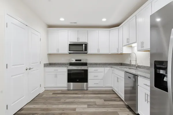 a kitchen with granite countertop white cabinets and stainless steel appliances