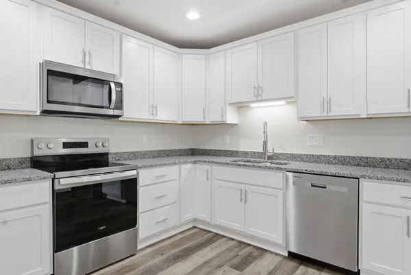 a kitchen with granite countertop white cabinets and stainless steel appliances