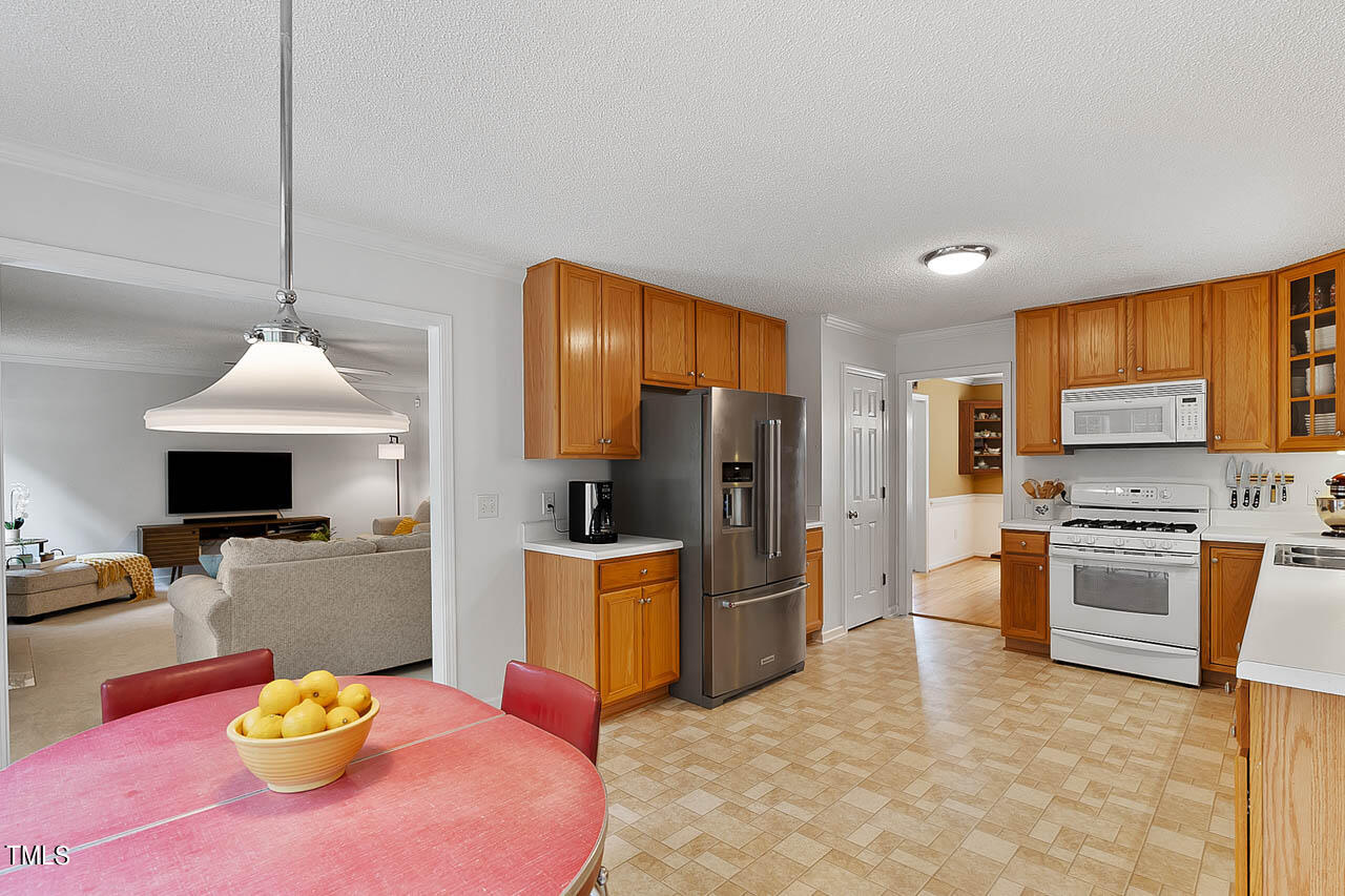 1060 Alderman Circle Raleigh, NC 27603 - Photo 11 of 30 a kitchen with stainless steel appliances granite countertop a sink a stove a refrigerator a stove a dining table and chairs with wooden floor