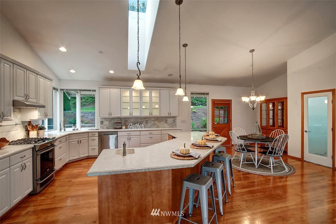 11225 Renton Issaquah Road Southeast Issaquah, WA 98027 - Photo 6 of 21 a kitchen with stainless steel appliances kitchen island granite countertop a stove a sink a dining table and chairs with wooden floor