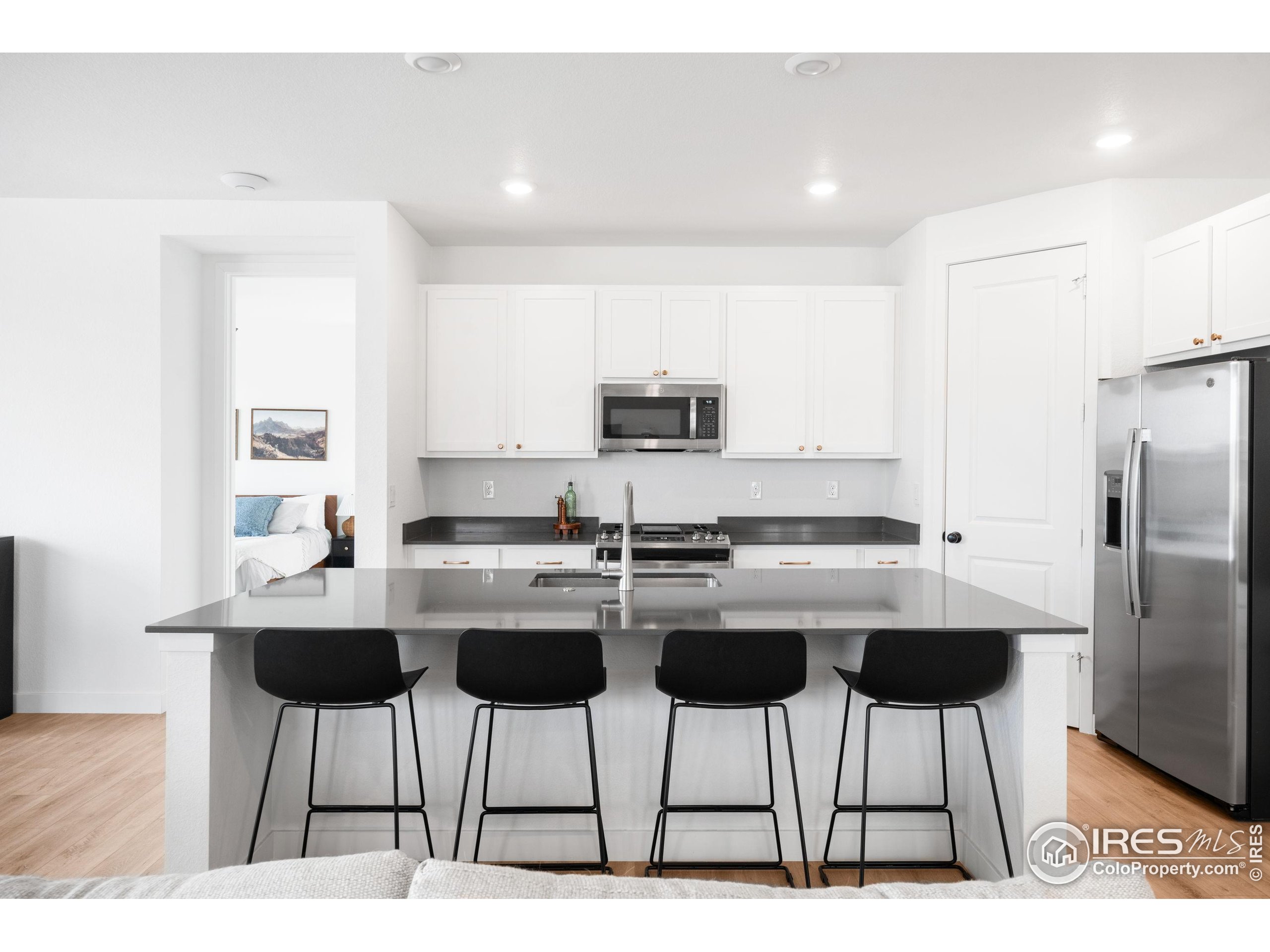 840 Clover Loop Lafayette, CO 80026 - Photo 9 of 39 a kitchen with stainless steel appliances kitchen island a dining table chairs and a refrigerator