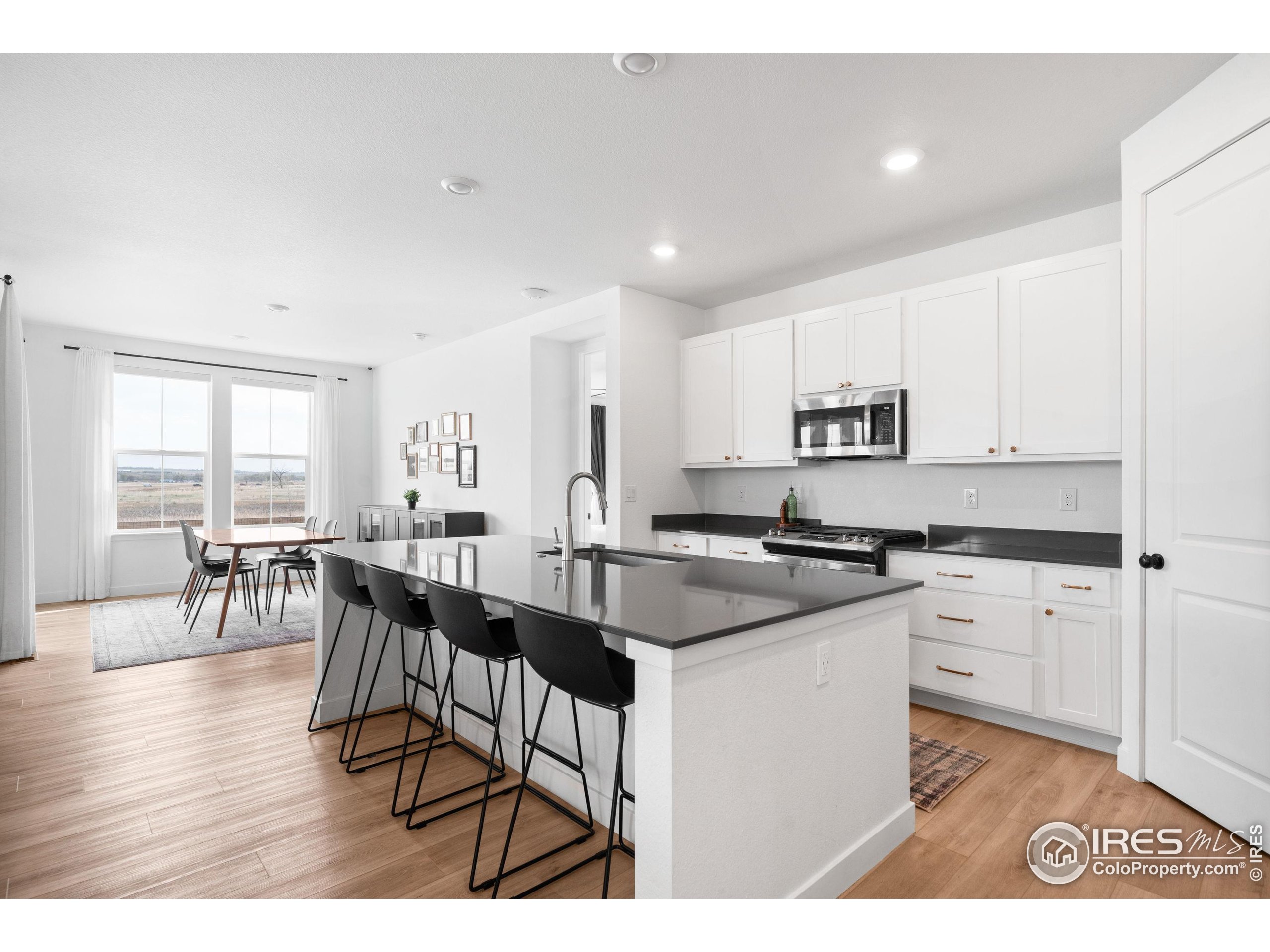 840 Clover Loop Lafayette, CO 80026 - Photo 10 of 39 a kitchen with stainless steel appliances kitchen island granite countertop a stove a sink a dining table and chairs