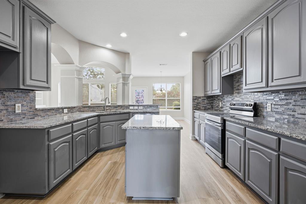 1904 Meera Lane Mansfield, TX 76063 - Photo 18 of 35 a kitchen with stainless steel appliances granite countertop a stove top oven a sink dishwasher and a refrigerator with wooden floor