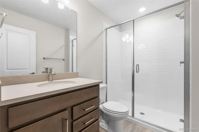 a bathroom with a sink a toilet a mirror and shower