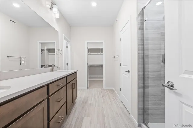 a spacious bathroom with a double vanity sink a mirror and a shower