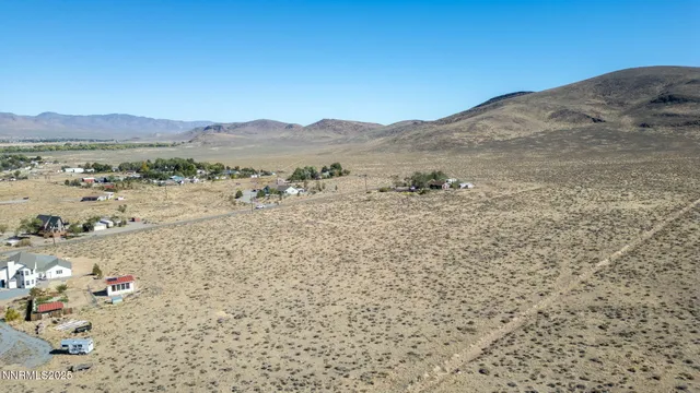 a view of a dry yard with mountain and trees