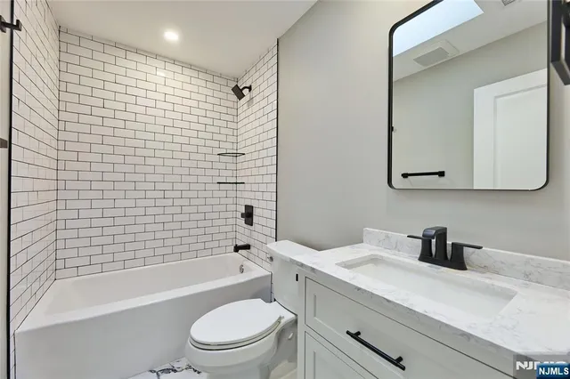 a bathroom with a bathtub shower sink mirror vanity and toilet