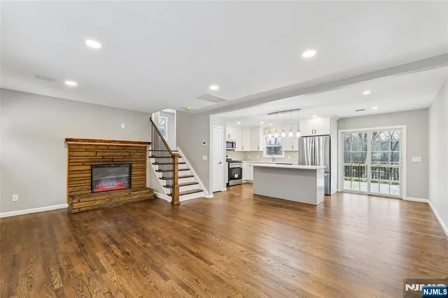 a view of an empty room with wooden floor fireplace and a window