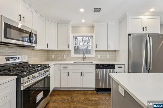 a kitchen with stainless steel appliances granite countertop a stove top oven a sink and a refrigerator