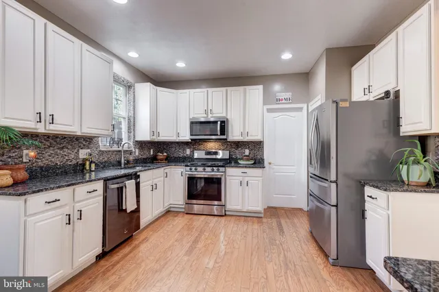 a kitchen with granite countertop a stove a sink a refrigerator a dining table and chairs