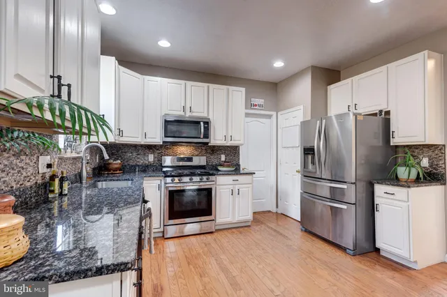 a kitchen with stainless steel appliances granite countertop a stove top oven a sink a dining table and chairs