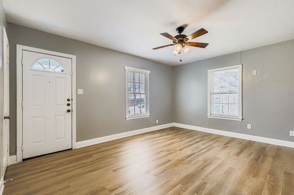 700 West St Johns Avenue Austin, TX 78752 - Photo 4 of 16 an empty room with wooden floor a ceiling fan and windows