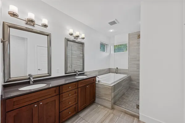 a bathroom with a sink double vanity granite tub and a mirror